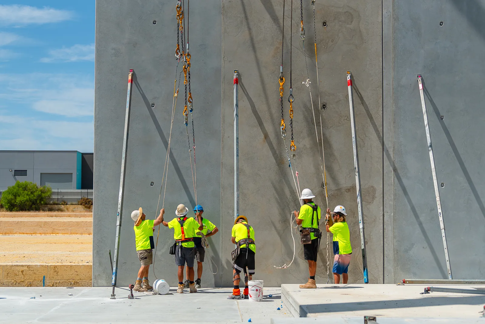 a team in safety gear standing next to a large freshly erected concrete panel